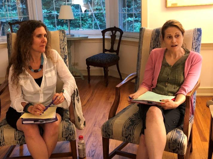 Two women sitting in chairs participating in discussion.