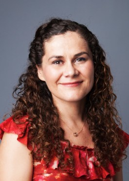 Ligia Mihut smiles at the camers and poses in front of a blue background