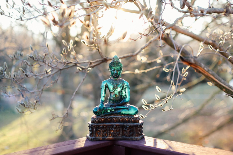 Photo of translucent Buddha statue seated outdoors catches the light from the sunrise.